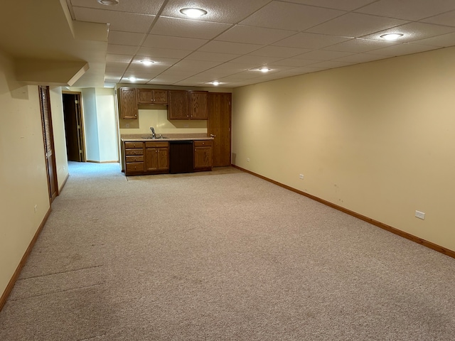 unfurnished living room featuring a drop ceiling, light colored carpet, and sink