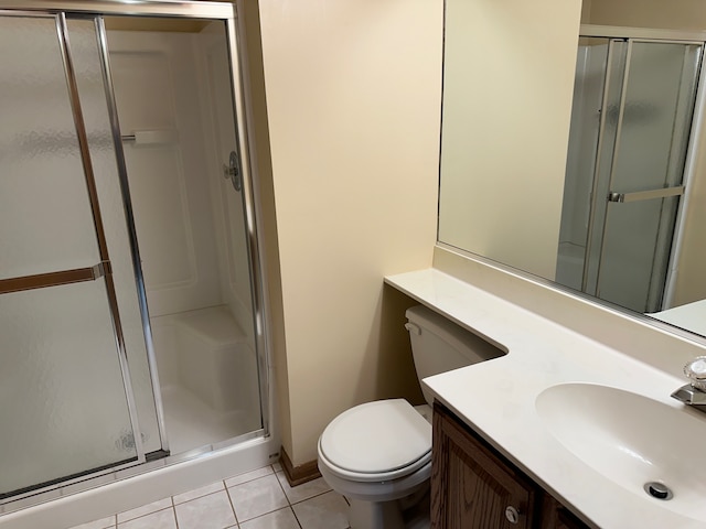 bathroom with tile patterned flooring, vanity, toilet, and a shower with door