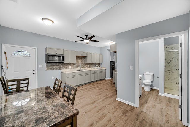 kitchen featuring ceiling fan, sink, tasteful backsplash, gray cabinetry, and light wood-type flooring