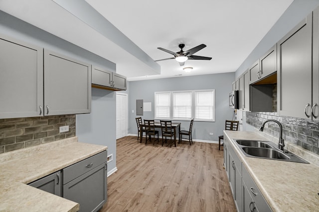 kitchen featuring gray cabinetry, light wood-type flooring, ceiling fan, and tasteful backsplash