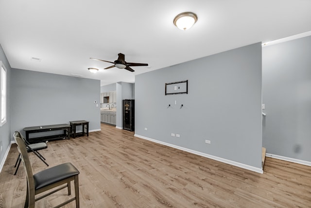 living room with ceiling fan, light hardwood / wood-style flooring, and sink