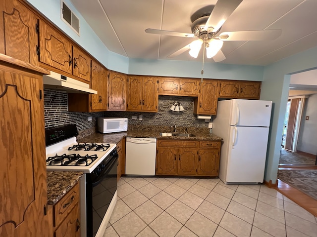 kitchen with tasteful backsplash, white appliances, ceiling fan, dark stone counters, and sink