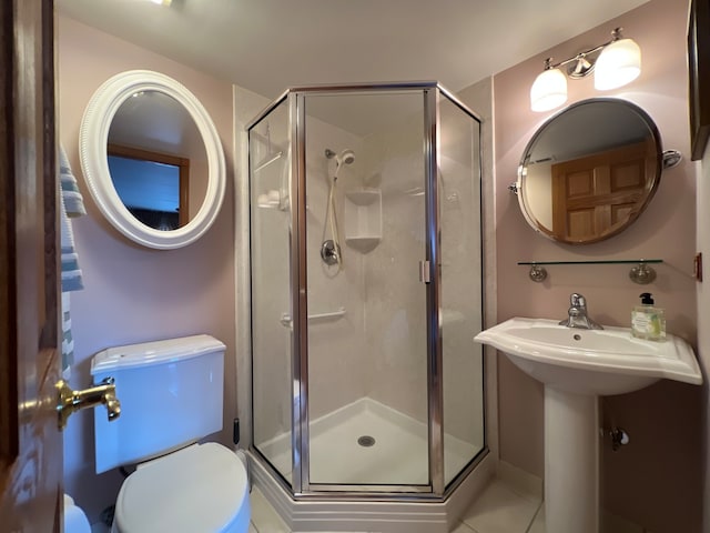 bathroom featuring tile patterned flooring, toilet, and a shower with door