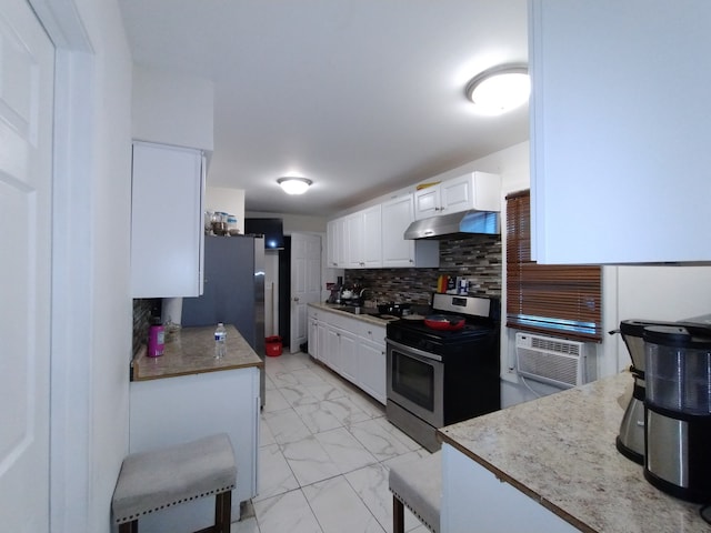 kitchen with tasteful backsplash, sink, stainless steel stove, white cabinetry, and refrigerator