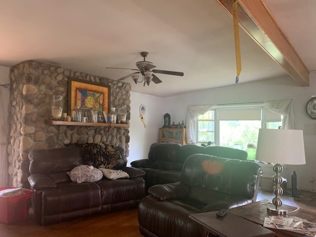 living room with ceiling fan, a stone fireplace, hardwood / wood-style flooring, and beamed ceiling