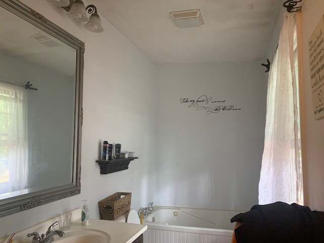 bathroom featuring vanity and a relaxing tiled tub