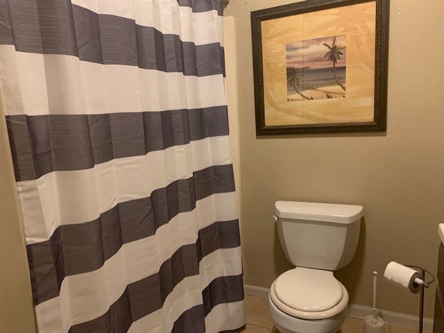 bathroom featuring curtained shower, toilet, and tile patterned floors