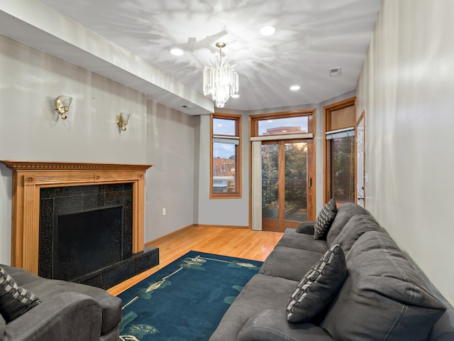 living room with wood-type flooring, an inviting chandelier, and a premium fireplace