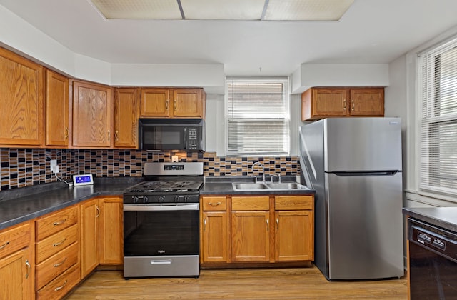 kitchen featuring decorative backsplash, black appliances, light hardwood / wood-style floors, and sink