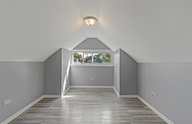 additional living space featuring lofted ceiling and light hardwood / wood-style flooring