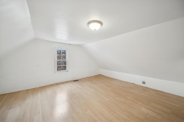 bonus room with vaulted ceiling and light wood-type flooring