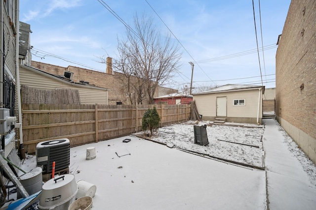 yard covered in snow with central AC unit and an outbuilding