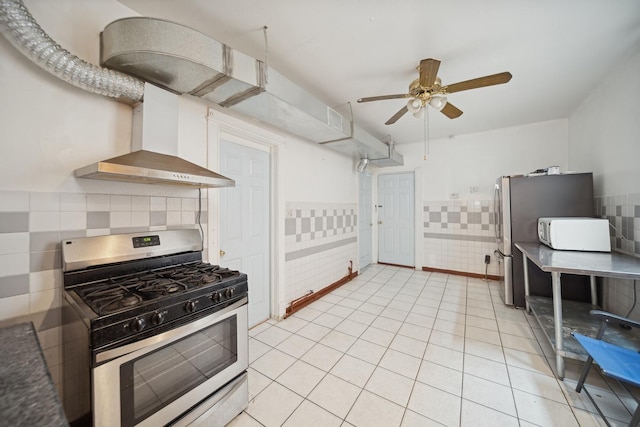 kitchen featuring stainless steel appliances, light tile patterned floors, ceiling fan, and wall chimney exhaust hood