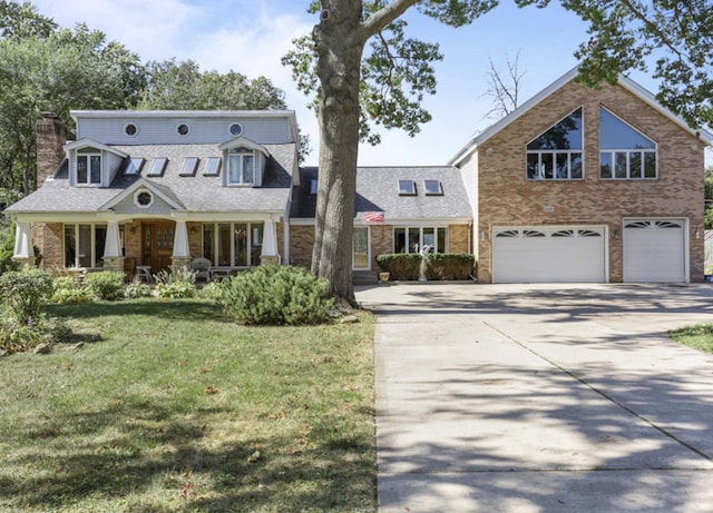 view of front of home featuring a front lawn, a chimney, brick siding, an attached garage, and driveway