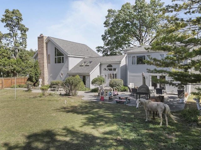 rear view of house with fence, roof with shingles, a chimney, a patio area, and a lawn