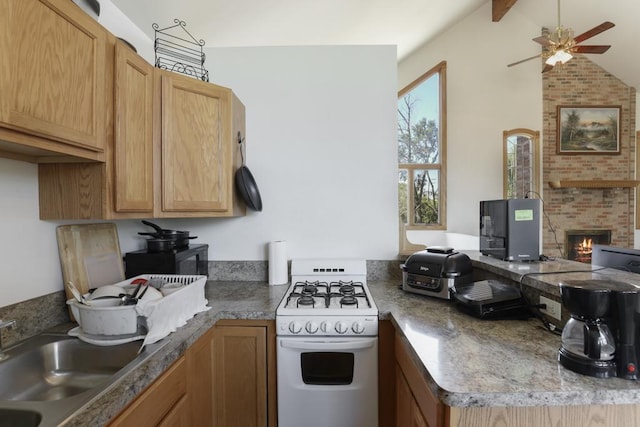 kitchen with a sink, a brick fireplace, white gas range, a peninsula, and a ceiling fan