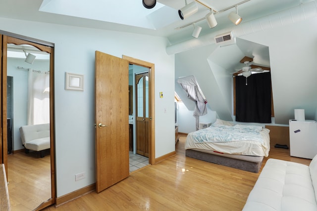 bedroom with light wood-type flooring, vaulted ceiling, ceiling fan, and track lighting