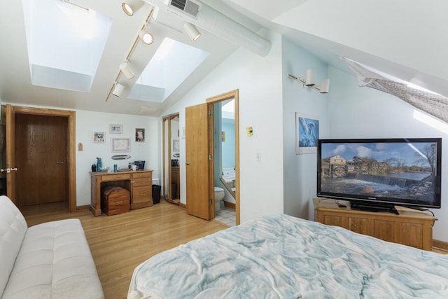 bedroom featuring visible vents, baseboards, vaulted ceiling with skylight, rail lighting, and light wood finished floors