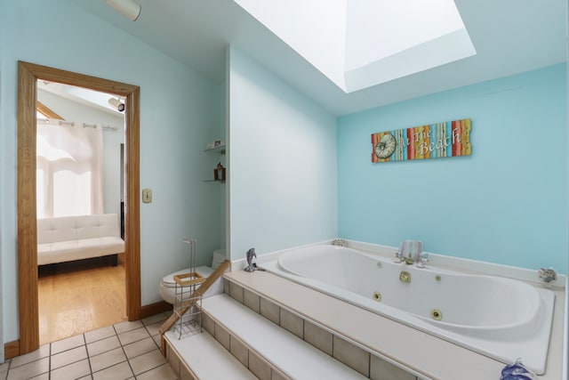 bathroom featuring tile patterned flooring, vaulted ceiling, a washtub, and toilet