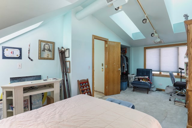 carpeted bedroom featuring rail lighting, vaulted ceiling with skylight, and a closet