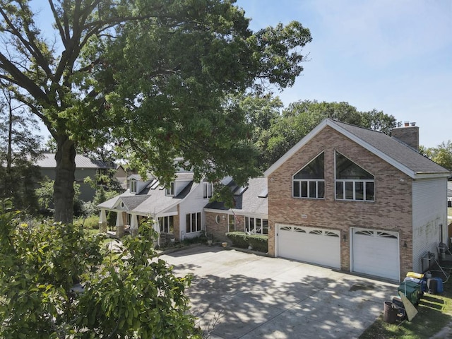 view of front of home with brick siding, a garage, a chimney, and concrete driveway