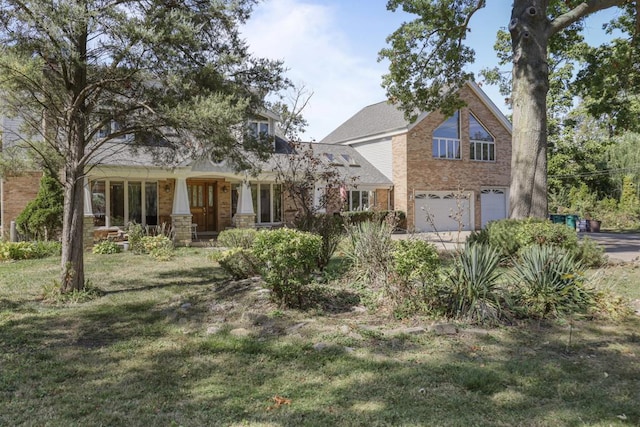 traditional home featuring a porch, driveway, a front yard, brick siding, and an attached garage