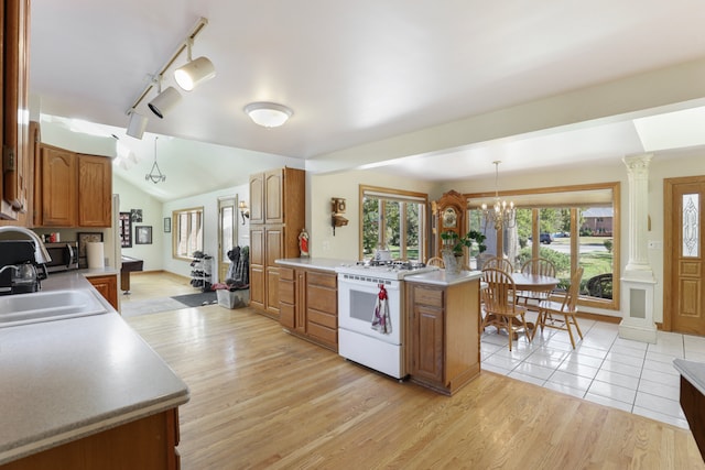 kitchen with lofted ceiling, hanging light fixtures, sink, light hardwood / wood-style flooring, and white range with gas cooktop