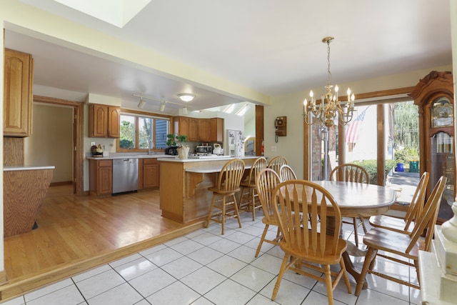 dining area featuring a notable chandelier, light hardwood / wood-style floors, a skylight, and plenty of natural light