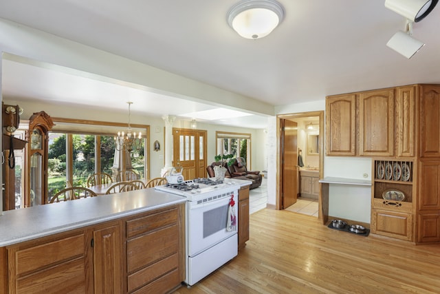 kitchen with a notable chandelier, light wood-type flooring, white stove, and decorative light fixtures