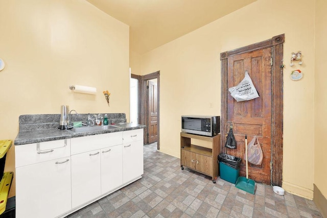 2333 W Huron St, Chicago, IL 60612 - kitchen featuring white cabinets, baseboards, stainless steel microwave, dark countertops, and a sink