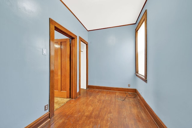 hallway with light hardwood / wood-style flooring, vaulted ceiling, plenty of natural light, and ornamental molding