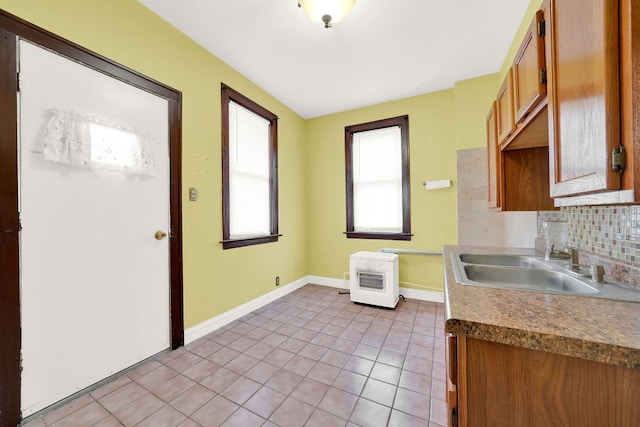 kitchen with heating unit, sink, light tile patterned floors, and tasteful backsplash