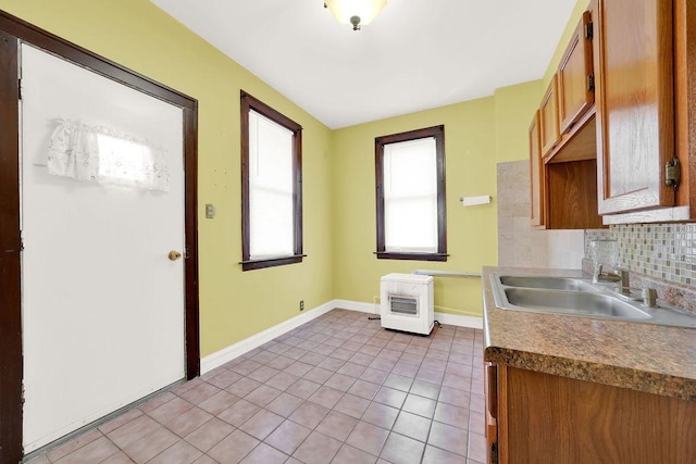 2333 W Huron St, Chicago, IL 60612 - kitchen with light tile patterned floors, baseboards, backsplash, a sink, and brown cabinetry