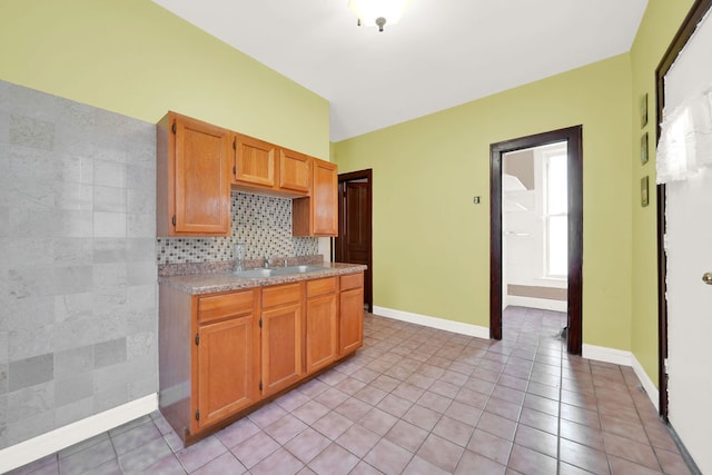 kitchen with tasteful backsplash, light tile patterned floors, and sink