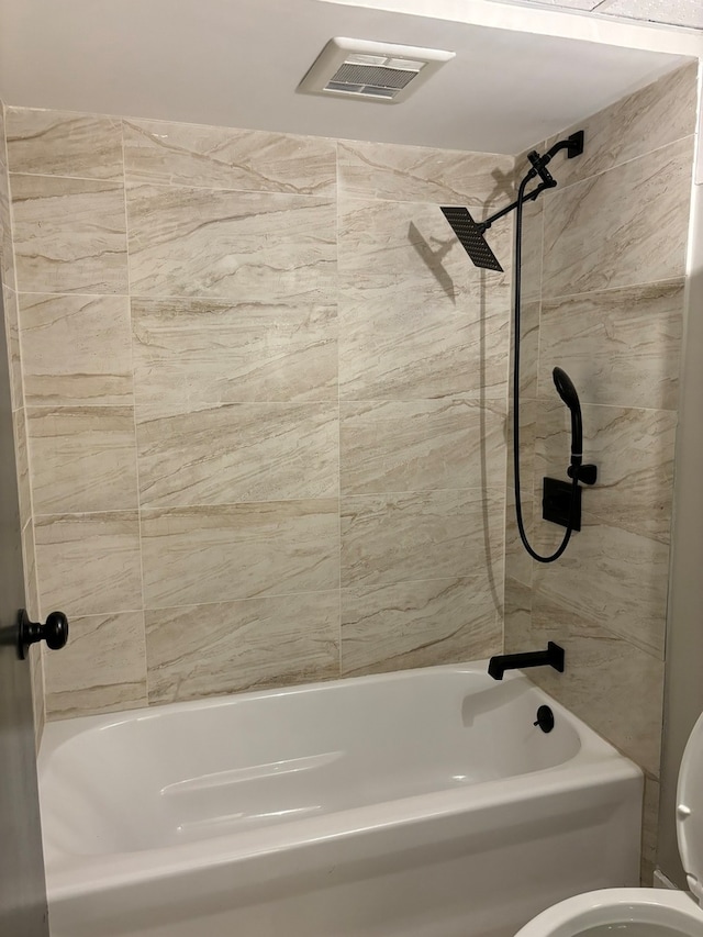 bathroom with tiled shower / bath combo and toilet