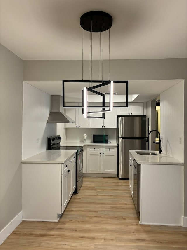 kitchen with sink, white cabinets, wall chimney exhaust hood, stainless steel appliances, and decorative light fixtures