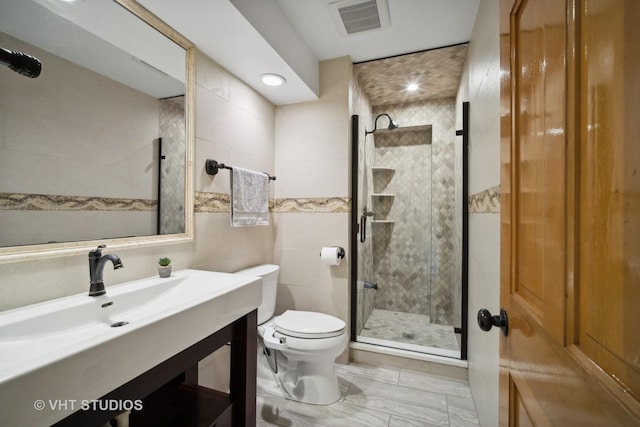 bathroom with vanity, toilet, a shower with door, and tile walls