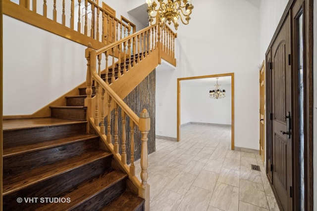 stairs featuring a towering ceiling and a chandelier