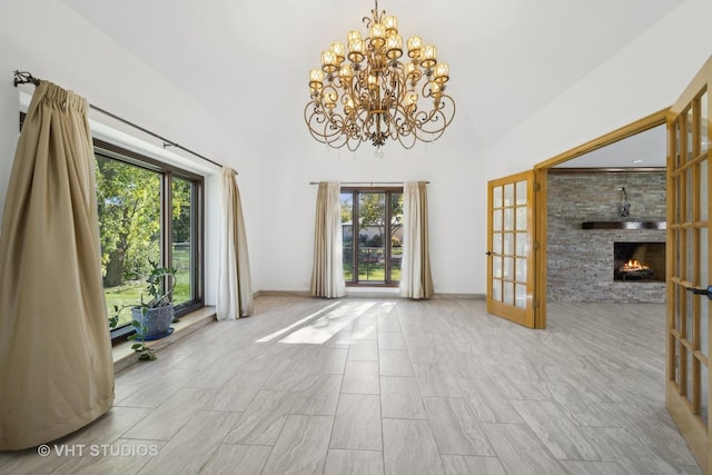 interior space with an inviting chandelier, a wealth of natural light, a fireplace, and french doors