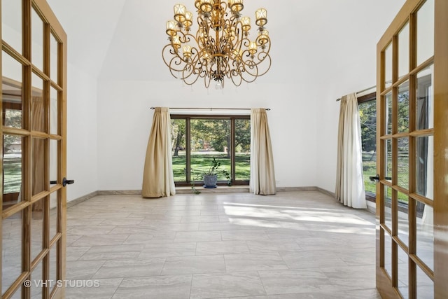 empty room with a high ceiling, a chandelier, and french doors