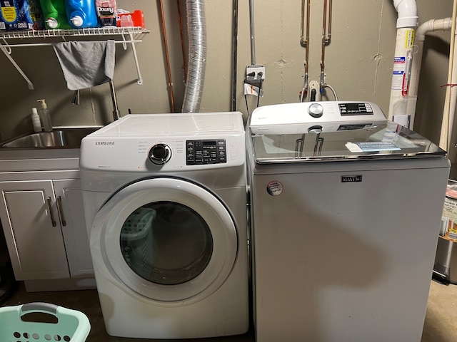 laundry area featuring washer and clothes dryer and cabinets