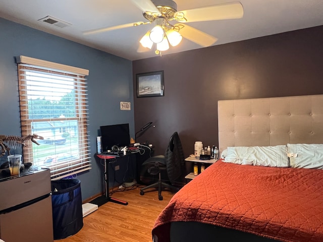 bedroom with light hardwood / wood-style floors, ceiling fan, and refrigerator