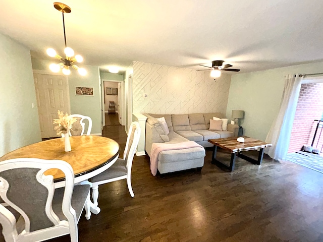 living room with ceiling fan with notable chandelier and dark hardwood / wood-style floors