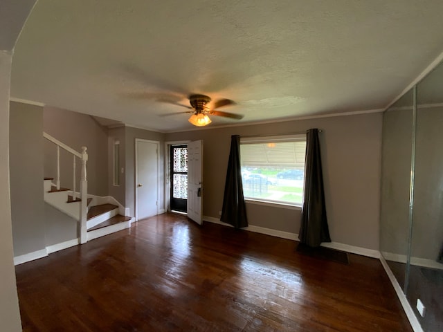 empty room with a textured ceiling, ceiling fan, crown molding, and dark hardwood / wood-style flooring