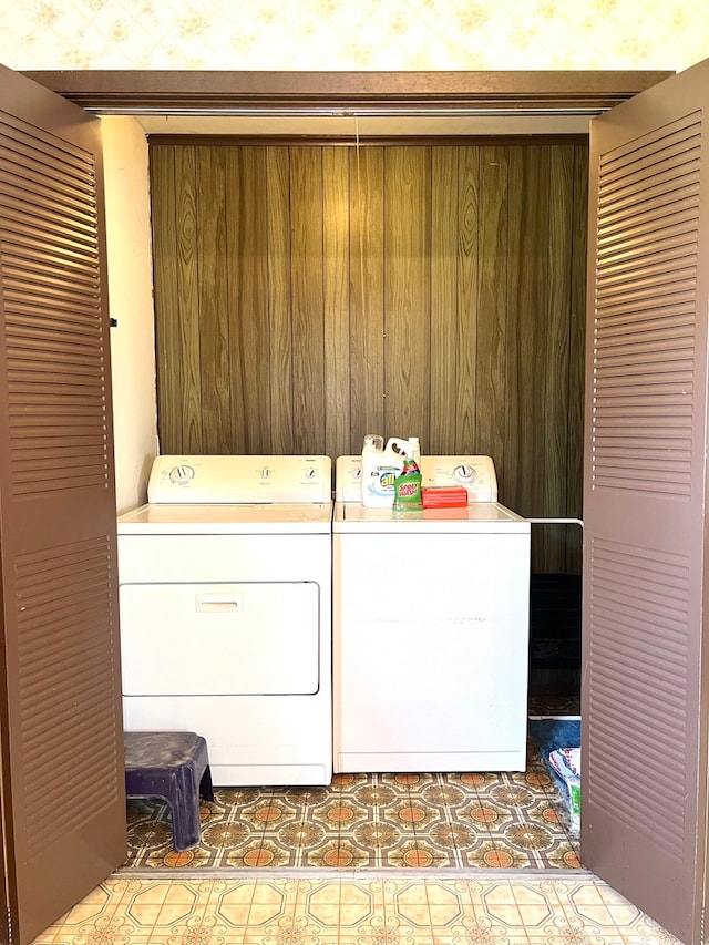 laundry area with wood walls and washer and dryer