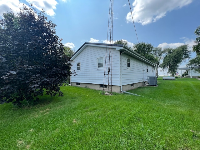 view of side of home featuring cooling unit and a yard