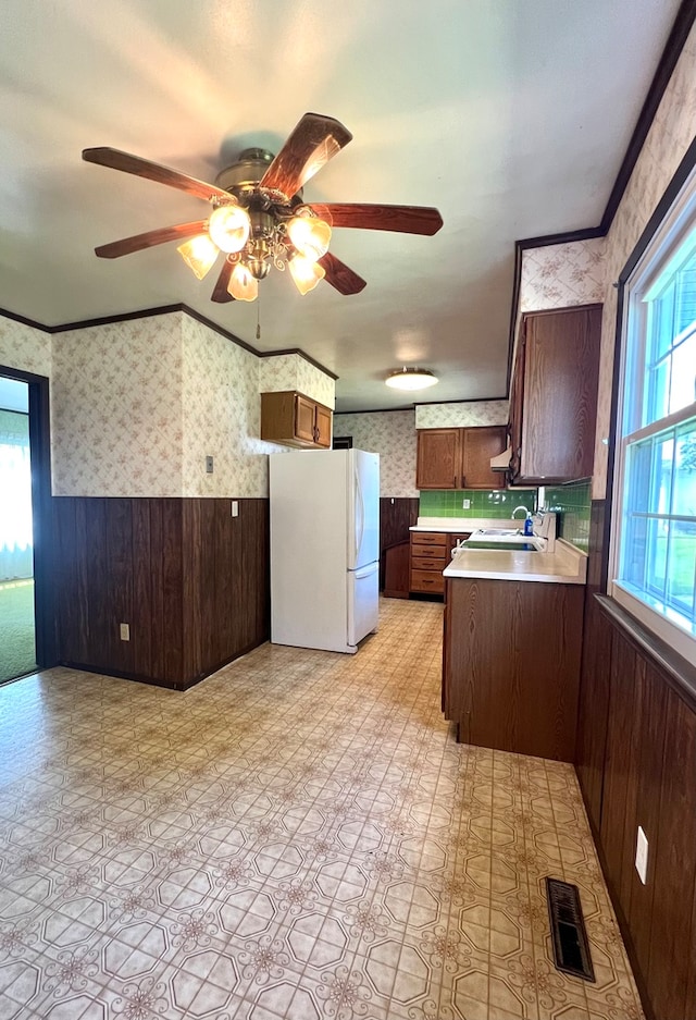 kitchen featuring wooden walls, sink, ceiling fan, and white refrigerator