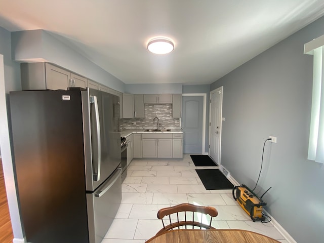 kitchen with appliances with stainless steel finishes, sink, gray cabinets, and tasteful backsplash