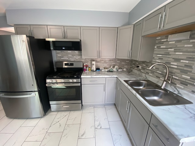 kitchen featuring decorative backsplash, stainless steel appliances, gray cabinets, and sink