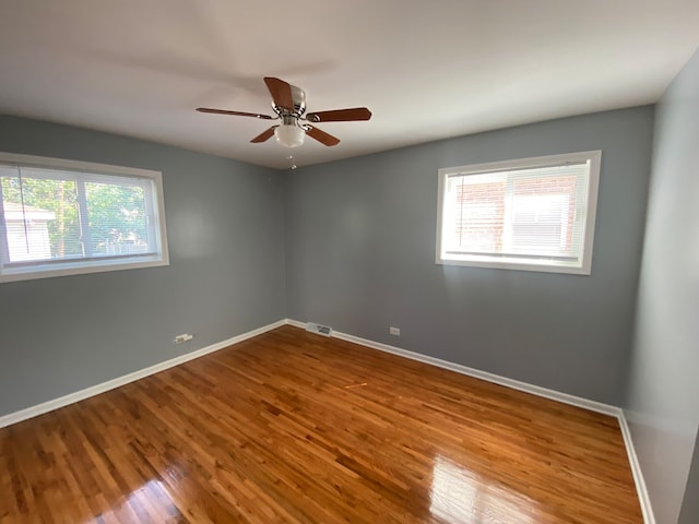 spare room featuring ceiling fan, hardwood / wood-style flooring, and a healthy amount of sunlight